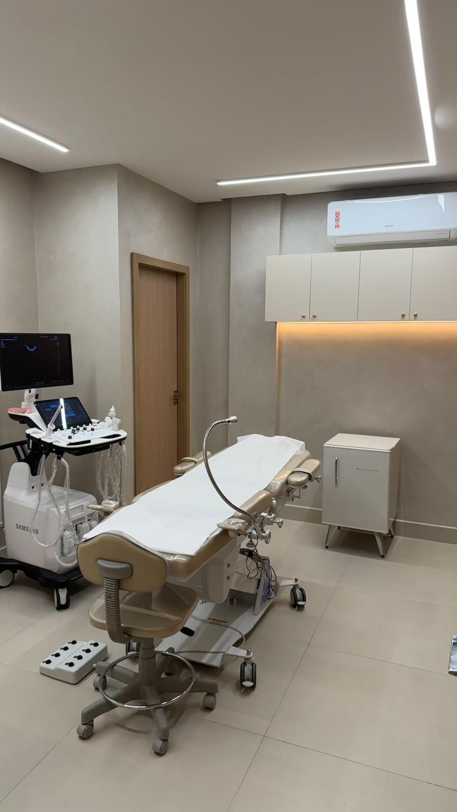 Sala de ultrassonografia com maca ginecológica e equipamento Samsung