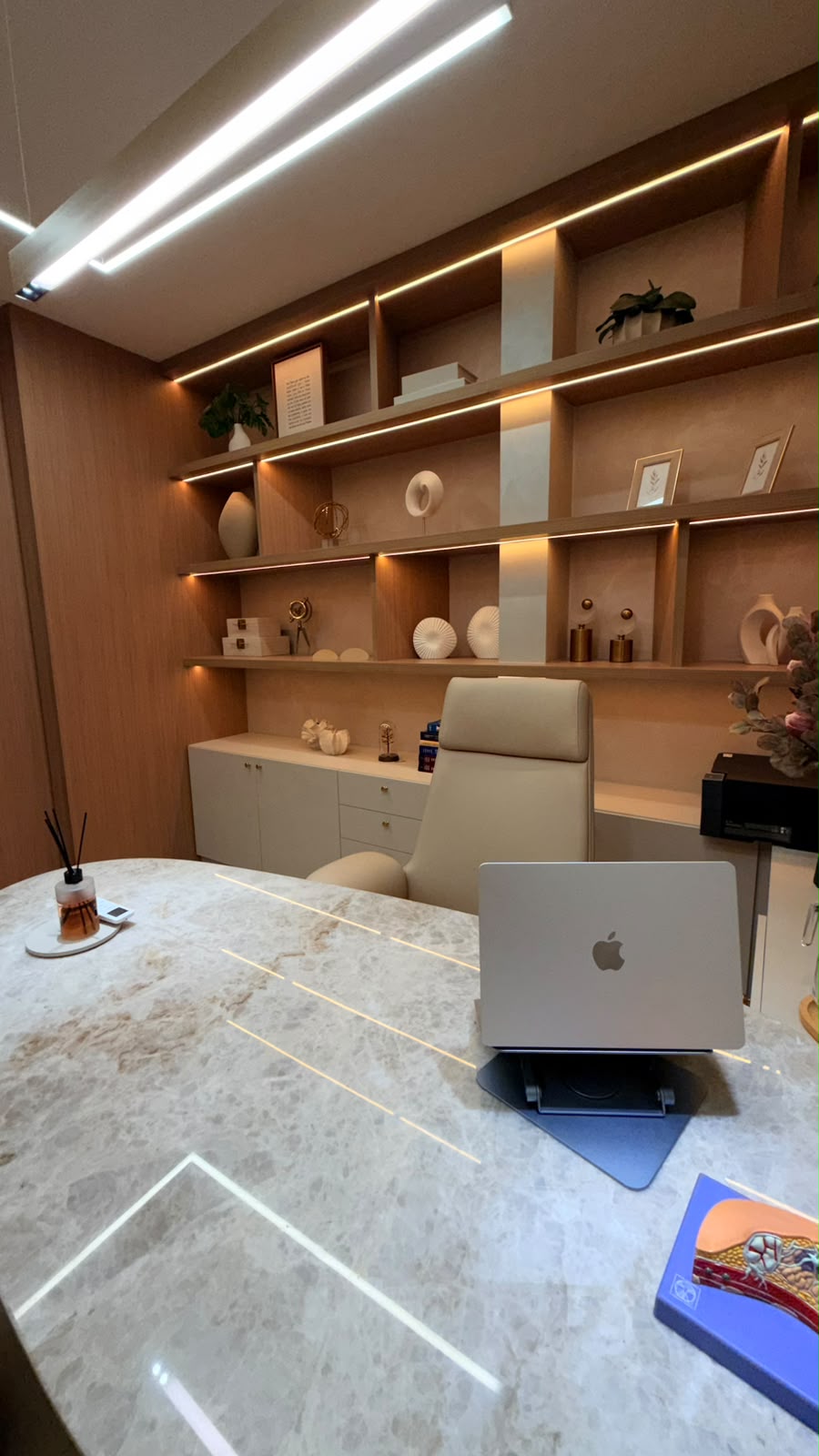 Detalhe da mesa de mármore e estante amadeirada com iluminação em LED
